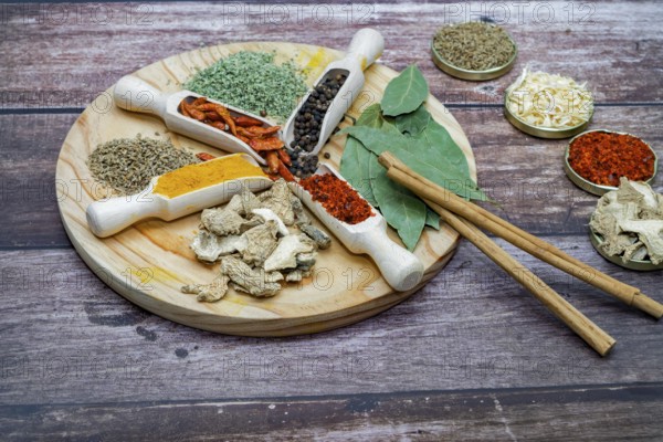 Different types of spices in wooden spoons on a wooden disk ginger, cayenne, pepper, cinnamon,