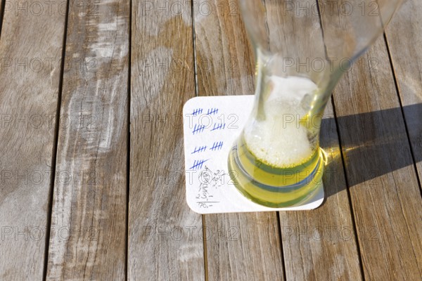 Empty beer glass on a beer mat with strokes