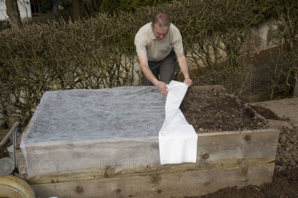 Man covers raised bed with fleece, mound bed, sowing, sowing, seeding
