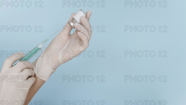 Hand with gloves holding syringe with vaccine copy space