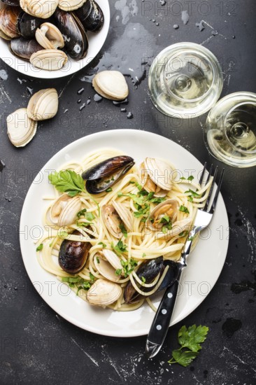 Spaghetti vongole, Italian seafood pasta with clams and mussels, in plate with herbs and two