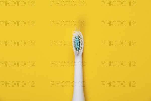 Used brush head of an electric toothbrush in front of a monochrome background