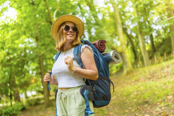 Beauty cheerful caucasian female backpacker enjoying nature while trekking in the forest
