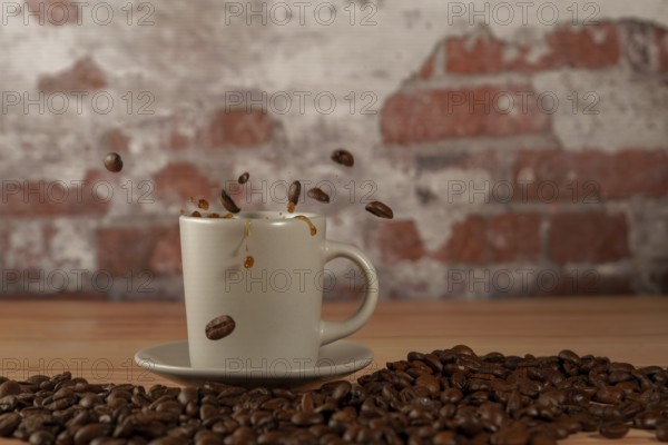 Appetizing cup of coffee with coffee beans splashing on a wooden table with a brick background