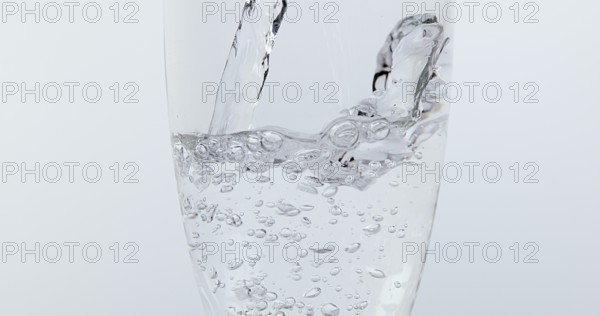 Water being poured into Glass against White Background