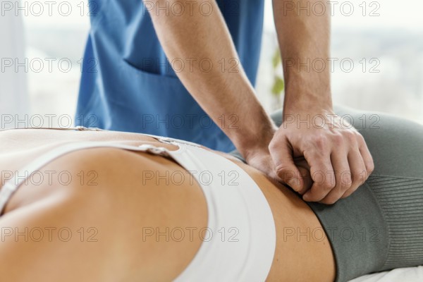 Male osteopathic therapist checking female patient s lower back spine