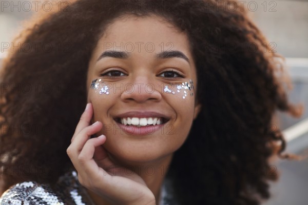 Close up portrait of overjoyed charming african american woman with curly hair and glitter on