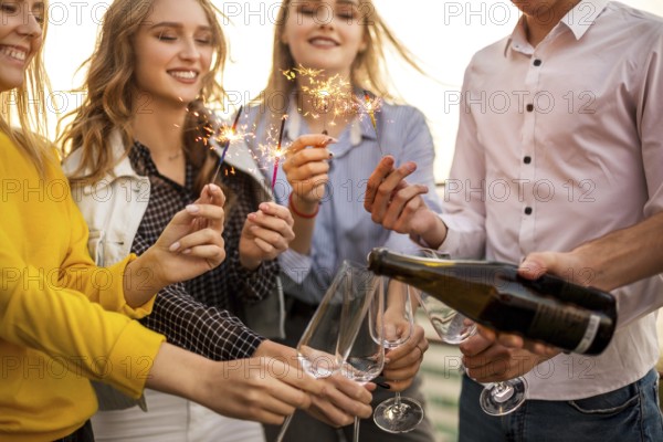 Group of partying friends with flutes with champagne and bengal fire having fun on the party on the