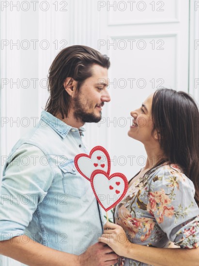 Couple holding paper hearts wooden stick