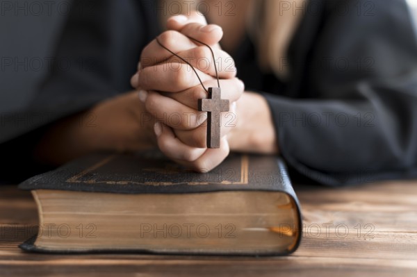 Person praying with cross holy book