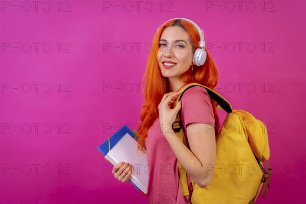 Redhead woman in studio photography dancing college student on a pink background, back to school