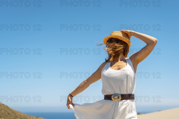 Cute woman holding her hat in a windy beach day in Cabo de Gata, Spain, Europe