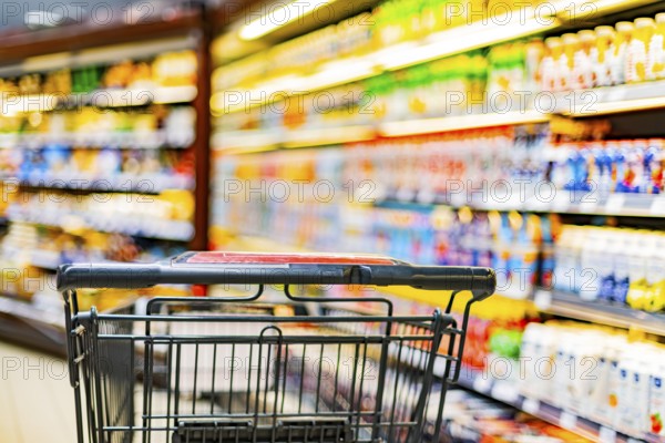 A shopping cart by a store shelf in a supermarket