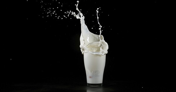 Glass of Milk Exploding against White Background