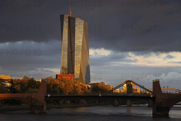 Dark clouds pass over the European Central Bank (ECB), illuminated by the last sunlight of the day,