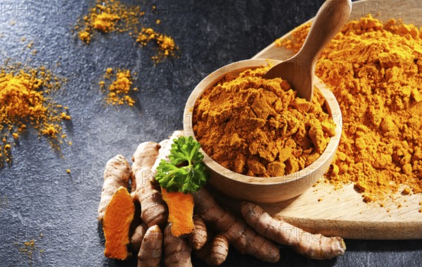 Composition with a bowl of ground turmeric and its fresh rhizome