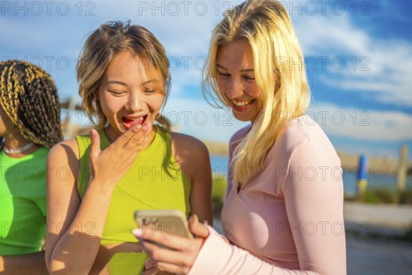 Chinese woman and blonde female friend sharing a mobile