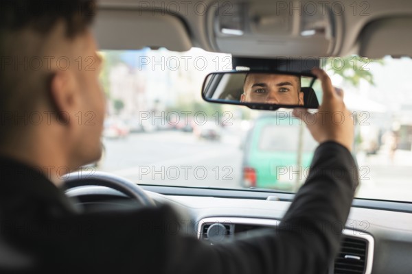 Young business man arranging his rear view mirror