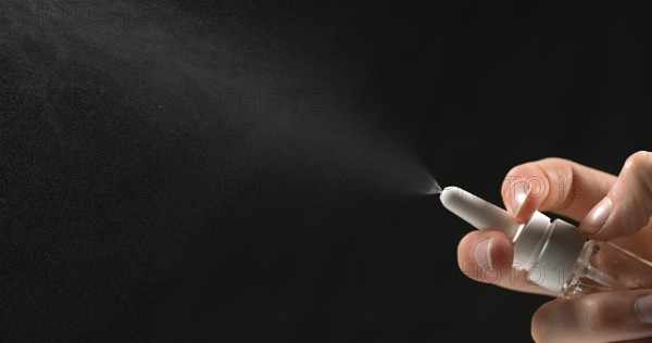 Hand of Woman and Nasal spray against Black Background