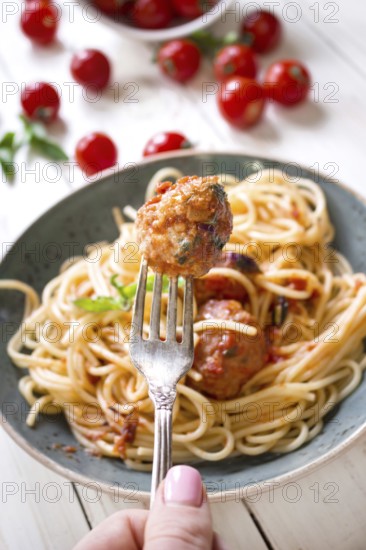 Close-up of delicious meatball on a fork. Spaghetti with meatballs and tomato sauce on a plate.