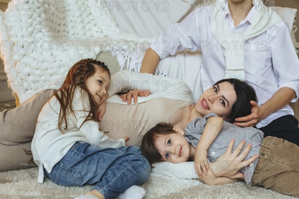 View from above of big family with two kids expecting new baby, waiting for third child. Pregnant