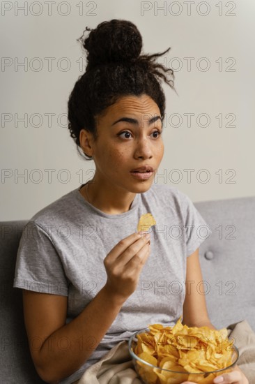 Woman couch watching tv eating chips