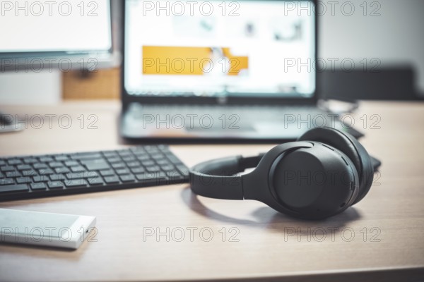 Wireless black headphones, mouse and keyboard on wooden desk