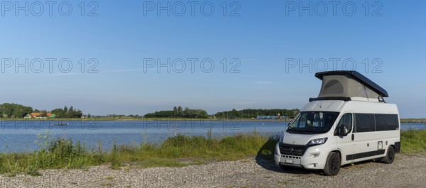 Tars, Denmark - 10 June, 2021- gray camper van parked on a gravel road at the ocean shore of
