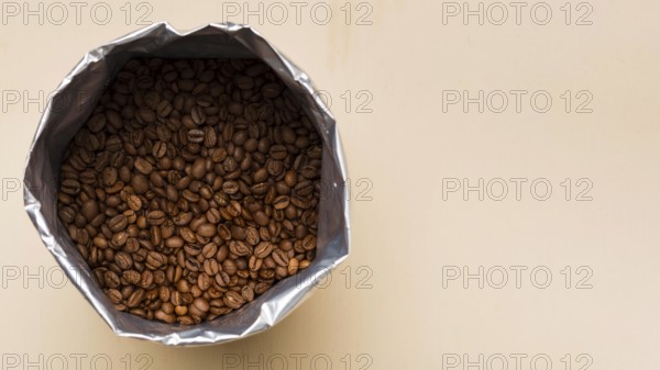 Black coffee beans beige background with copy space