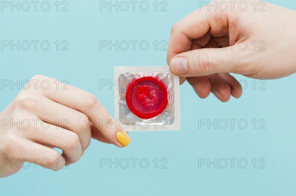 People holding red condom