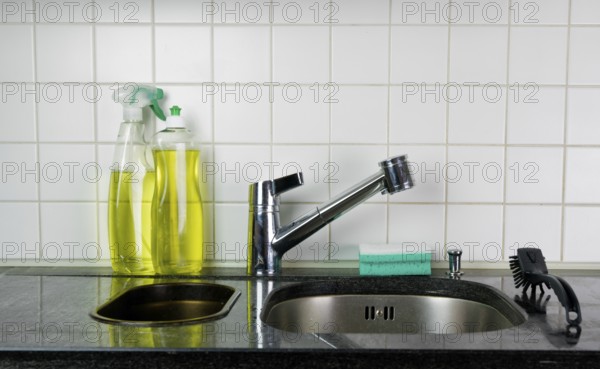 kitchen sink and faucet with a sponge and brush on a black granite table top and yellow kitchen