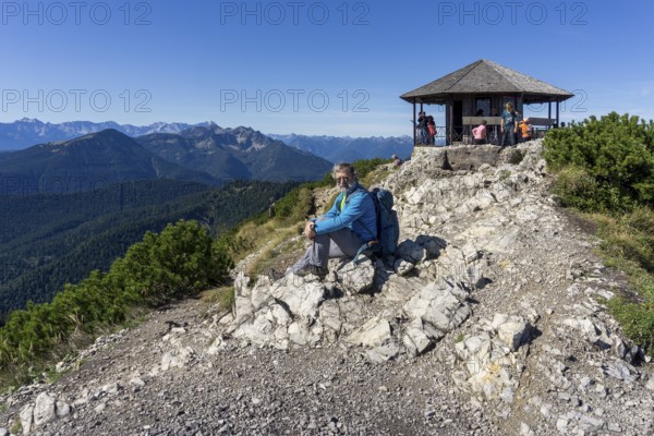 Hiker, senior, 64, resting in front of pavilion of King Ludwig II on the Herzogstand, Walchensee,