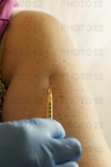Close-up of a woman's arm getting a vaccination in blue latex gloves