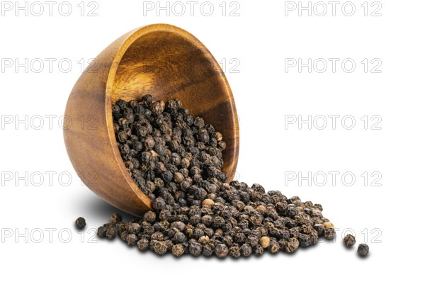 Closeup view pile of dried natural black pepper seeds in wooden cup on white background with