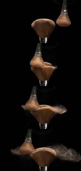 Make-up Brush spreading blush powder on black background