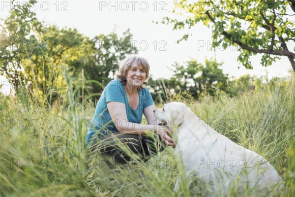 Elderly grayhaired woman with her lovely dog in the park. Portrait of a smiling senior female