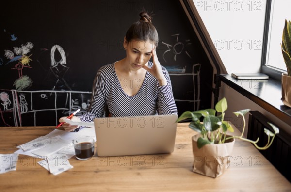 Serious housewife sits at table at home kitchen check household bills, make calculations on