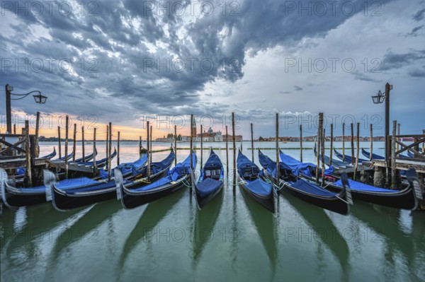 Gondolas in St Mark's Square in Venice, Italy, in front of a dramatic sunrise, Europe