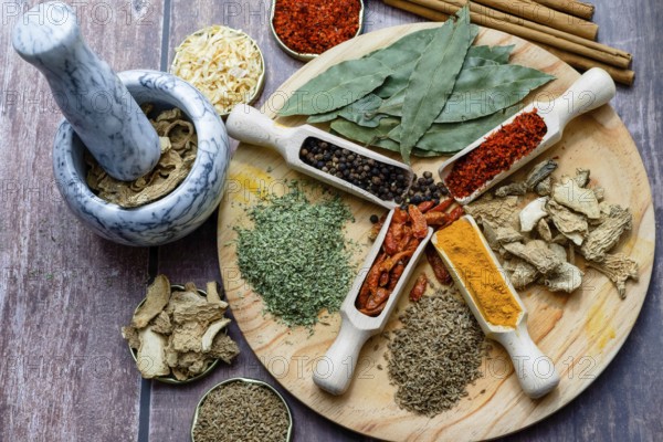 Different types of spices in wooden spoons on a wooden disk ginger, cayenne, pepper, cinnamon,