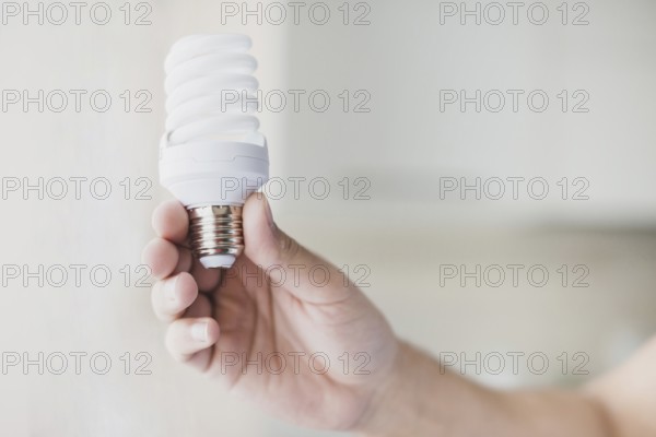 Human hand holding compact fluorescent light bulb