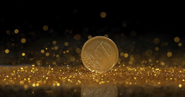 Coin of 1 Euro Rolling on Gold Powder against Black Background