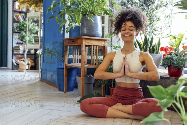 Young adult happy fit slim healthy African American ethnic woman wearing sportswear sitting in yoga