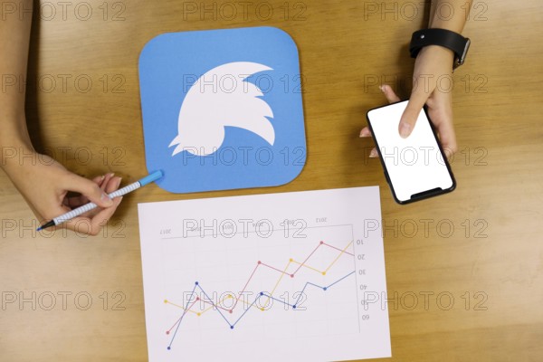 Person holding mobile phone analyzing twitter graph