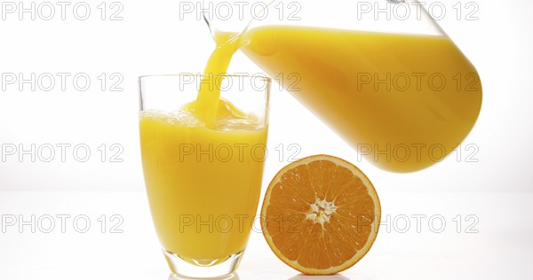 Orange Juice being poured into Glass against White Background