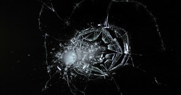 Golf Ball breaking Pane of Glass against Black Background