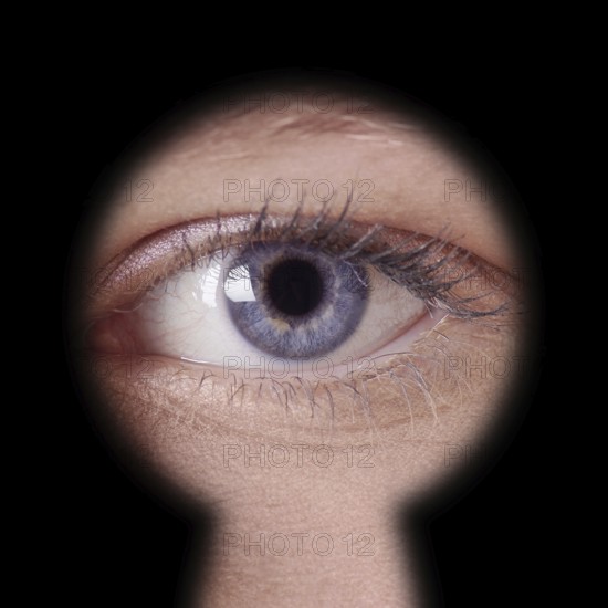 close-up of human female blue eye looking through keyhole