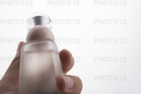 Little perfume glass bottle in hand on a white background