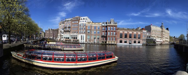 City tour ships are anchored at the Amstel in Amsterdam, Netherlands in spring. City tour ships