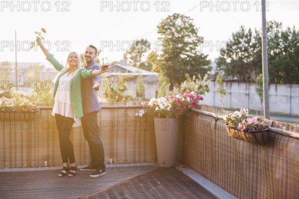 Portrait happy couple holding wineglass rose posing balcony