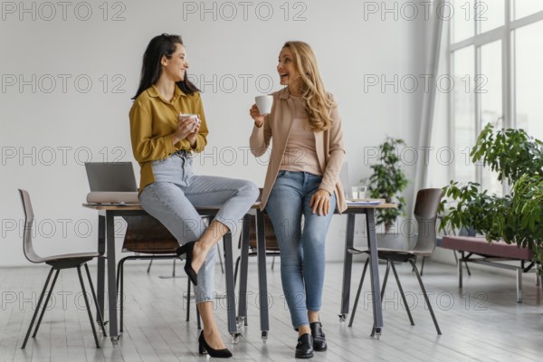 Businesswomen talking while enjoying cup coffee